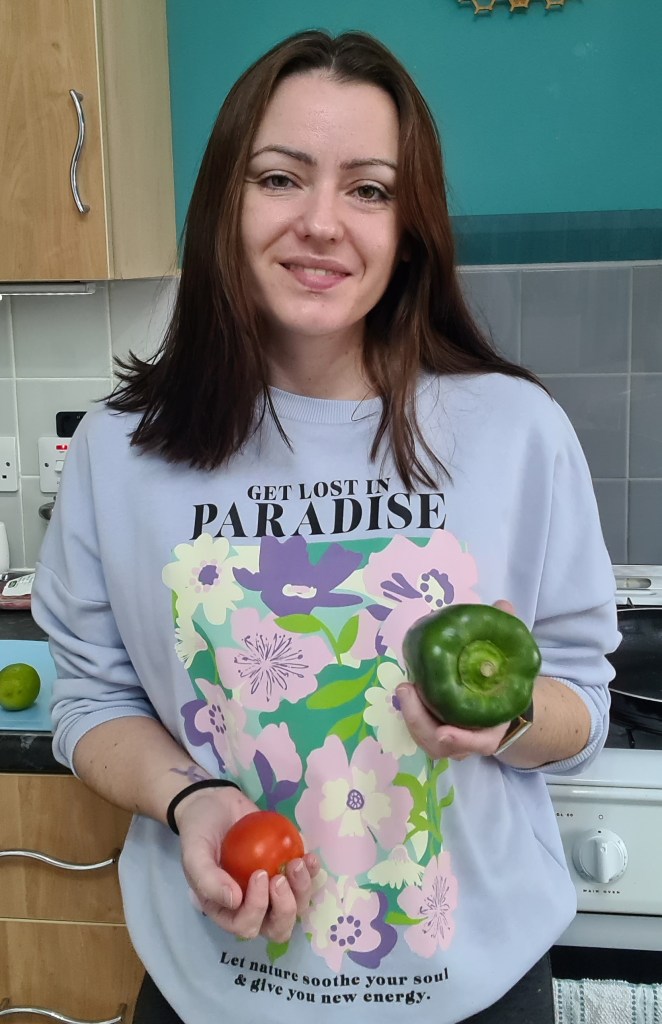 Sahara holding a tomato and a pepper